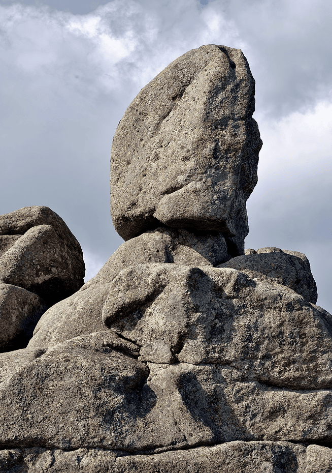 Tall rock formation under cloudy sky