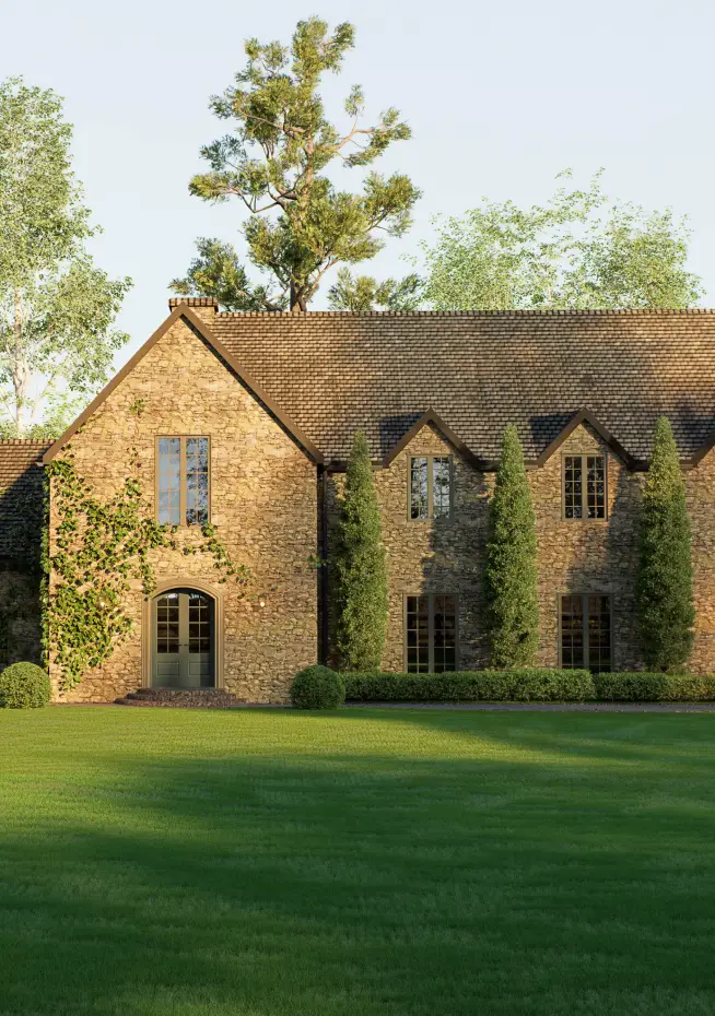 Traditional English country stone manor house featuring a detached garage, classic shingle roof, large green lawn, wooden fence, and beautiful landscaping.